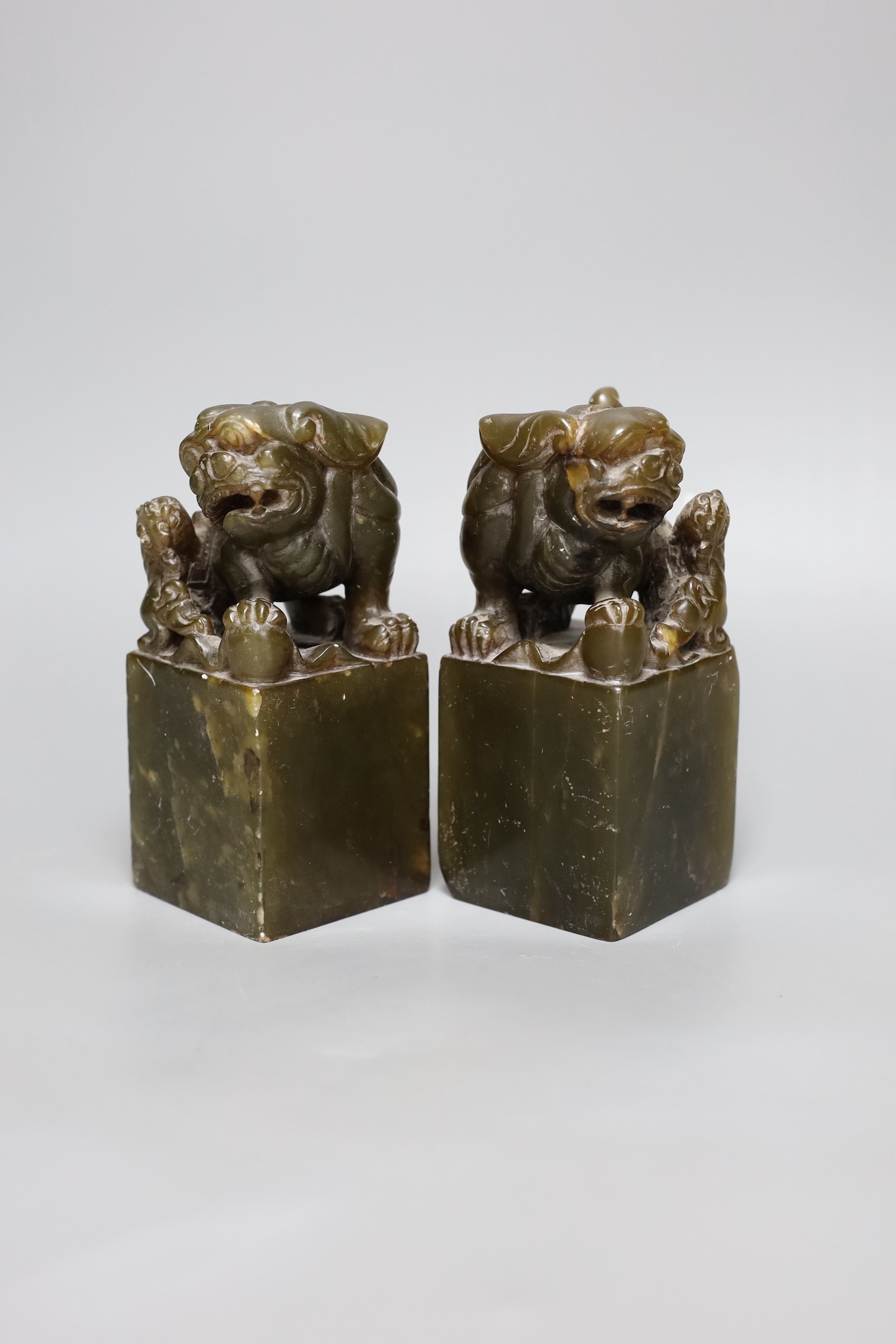 A pair of Chinese soapstone lion dog seals, 15 cms high